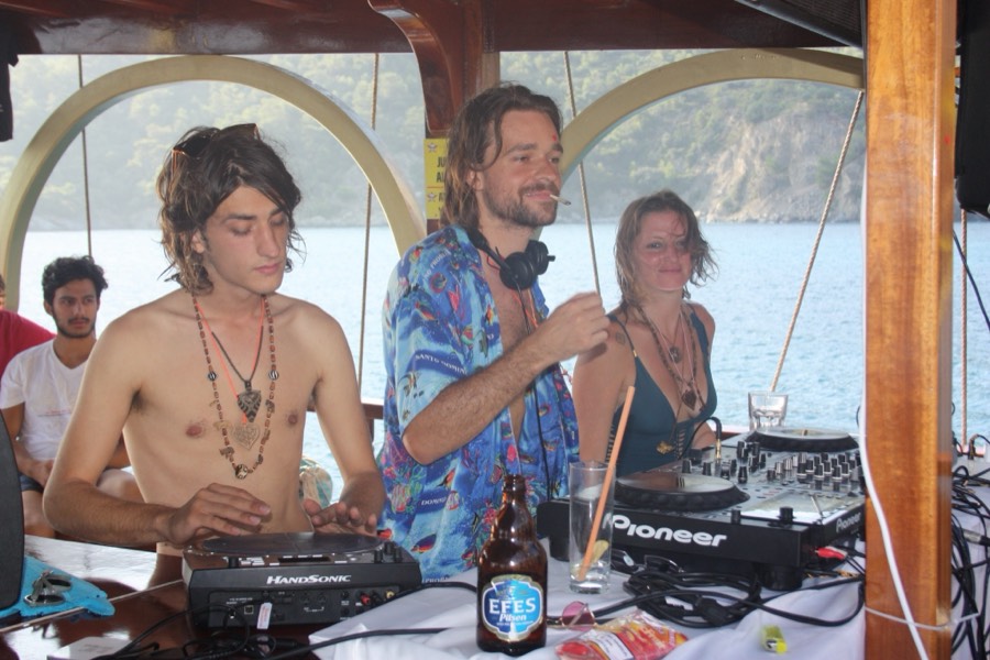 Three members playing music together behind the decks on a boat.