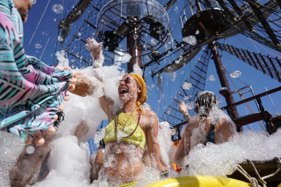 Members covered in foam with arms in the air on a boat deck.